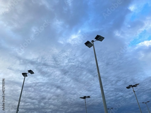 street lamp on sky. Lights posts at tennis courts agains blue sky and clouds.