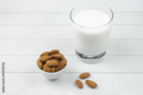 White ceramic bowl with almonds and and a glass of milk. Alternative milk concept