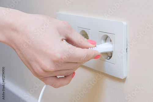 The woman pulls the electrical plug out of the socket wire