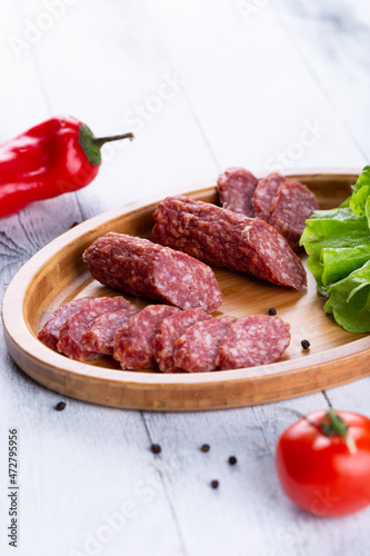 Fresh sausages and ham slices on wooden cutting board, delicious snack, spicy and high quality meat products made of pork and veal, beef.