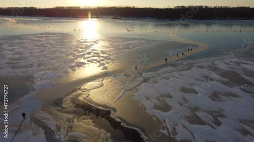 Ice skating people on a frozen lake during a beautiful winter sunset at the Drontermeer in The Netherlands. Aerial drone point of view. photo