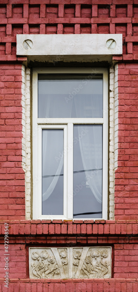 A modern plastic double-glazed window in the window of an old brick building with elements of stucco decoration. The picture was taken in Russia, in the city of Orenburg A modern plastic double-glazed window in the window of an old brick building with elements of stucco decoration. The picture was taken in Russia, in the city of Orenburg