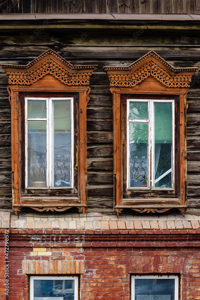 Windows with carved wooden frames, a fragment of the facade of an old building. The picture was taken in Russia, in the city of Orenburg