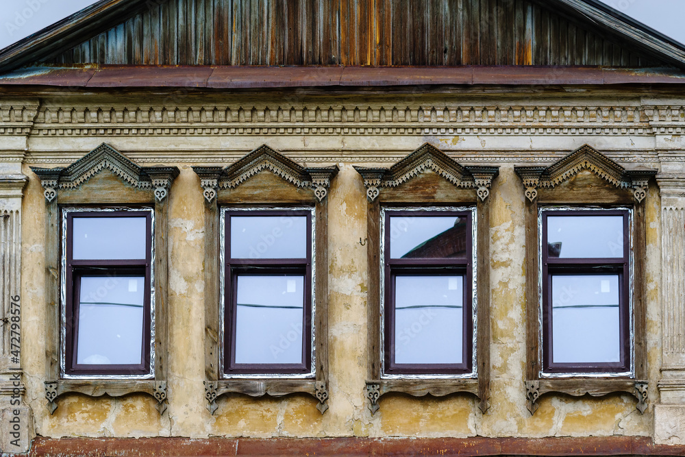 Carved wooden platbands on the windows of an old building, a fragment of the facade. The picture was taken in Russia, in the city of Orenburg