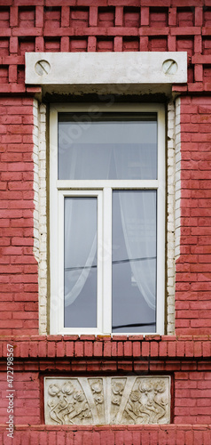 A modern plastic double-glazed window in the window of an old brick building with elements of stucco decoration. The picture was taken in Russia  in the city of Orenburg