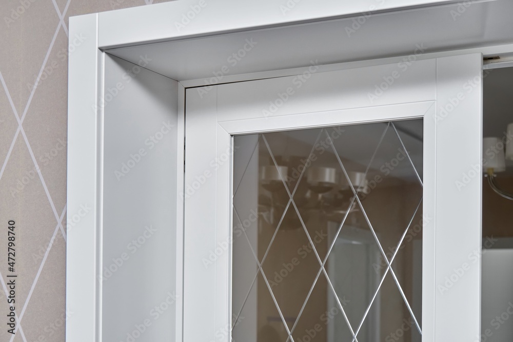 Fototapeta premium Elegant trendy inner doors with rhombus pattern on glass surface and silver handles in light spacious room of renovated apartment closeup