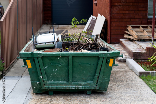 Skip bin with household waste rubbish on a front yard. House clean up concept. photo