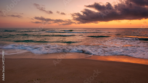 calm sea scenery at dawn. waves wash empty sandy beach at twilight. relax and summer vacation concept. warm velvet season weather with clouds on the sky