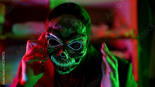 phone scammer calling by cell phone, person with gloomy skull mask with mobile photo