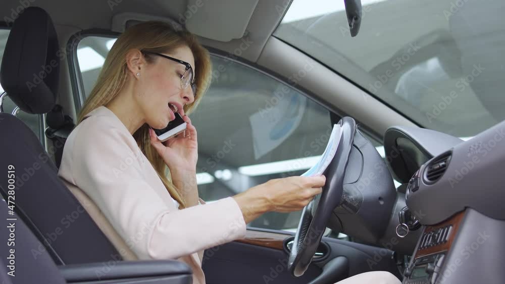 Attractive blond woman feeling anger, discussing report on phone sitting in car
