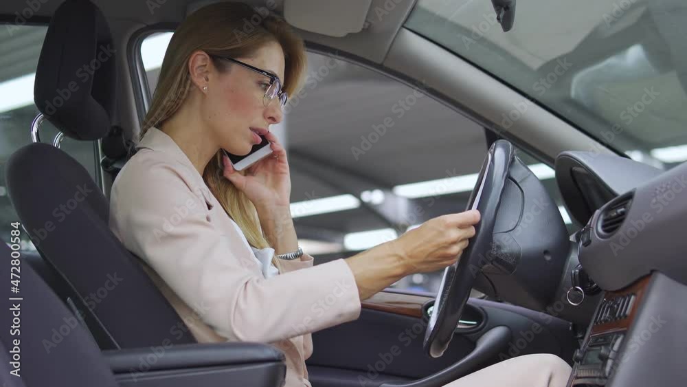 Serious business lady having phone conversation in car, checking documents Serious business lady having phone conversation in car, checking documents