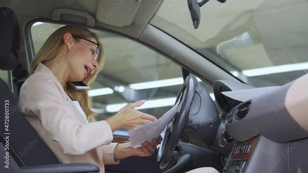 Angry annoyed lady boss in elegant business suit looking through documents before important meeting sitting in car, screaming at her secretary on phone, wrong or messed up documents, failure Angry annoyed lady boss in elegant business suit looking through documents before important meeting sitting in car, screaming at her secretary on phone, wrong or messed up documents, failure