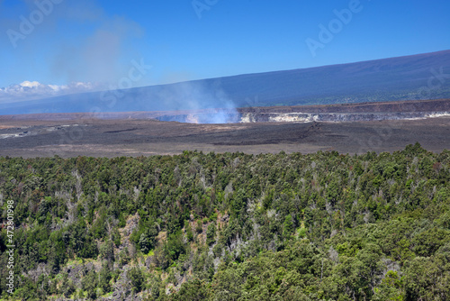 USA, Hawaii, Big Island of Hawaii. Hawaii Volcanoes National Park, View across forest near Kilauea Iki Crater towards eruption in Halemaumau Crater and distant slopes of Mauna Loa. photo