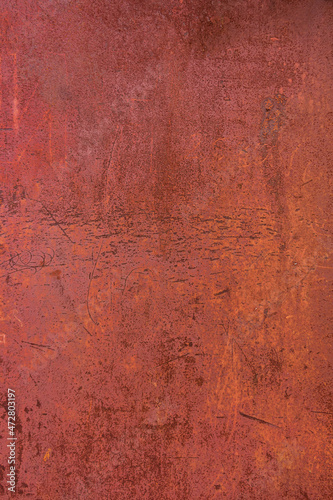 Metallic surface with rusting fencing and crumbling red paint.