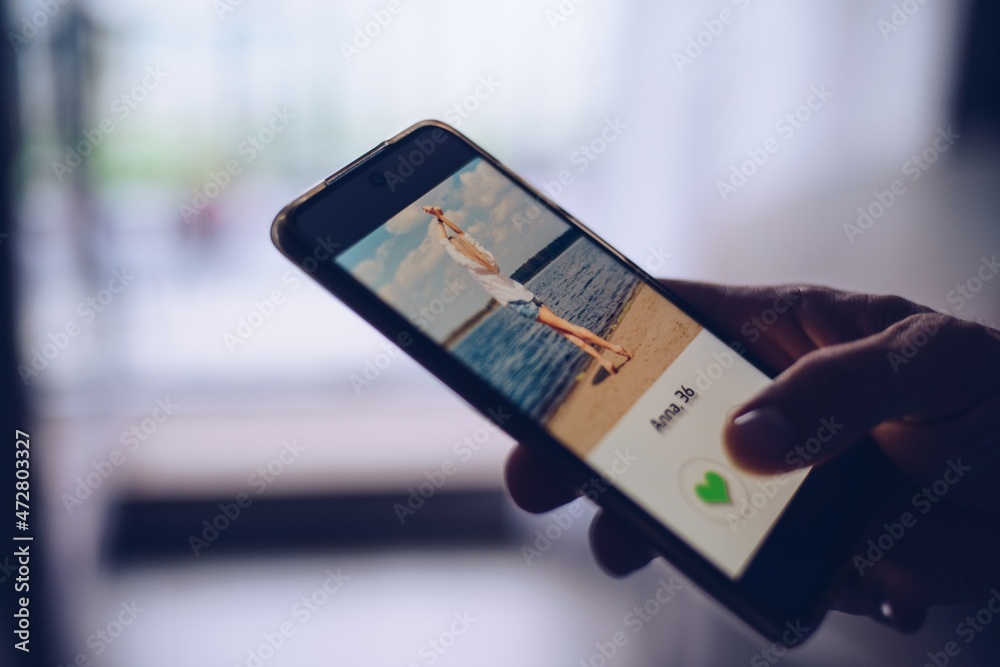 Finger of man pushing heart icon on screen in mobile smartphone application. Online dating app, valentine's day concept.