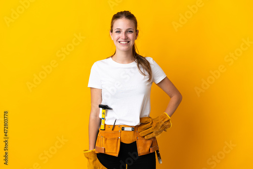 Young electrician woman isolated on yellow background laughing