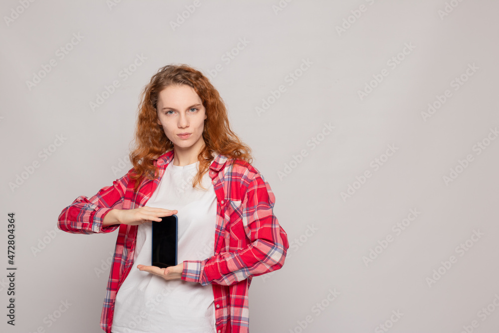 a young girl in a plaid shirt with a phone on a light background a young girl in a plaid shirt with a phone on a light background