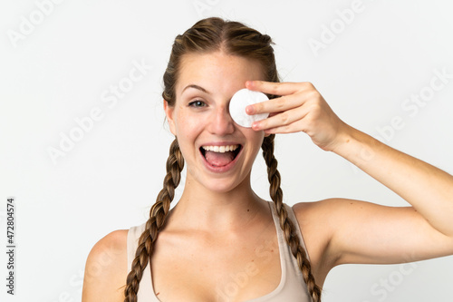 Young caucasian woman isolated on white background with cotton pad for removing makeup from her face and smiling