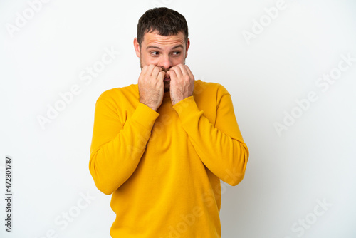 Young Brazilian man isolated on white background nervous and scared putting hands to mouth