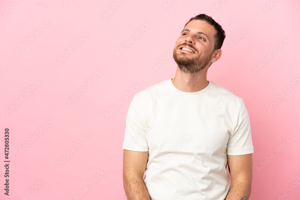 Young Brazilian man isolated on pink background thinking an idea while looking up
