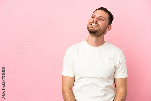 Young Brazilian man isolated on pink background thinking an idea while looking up