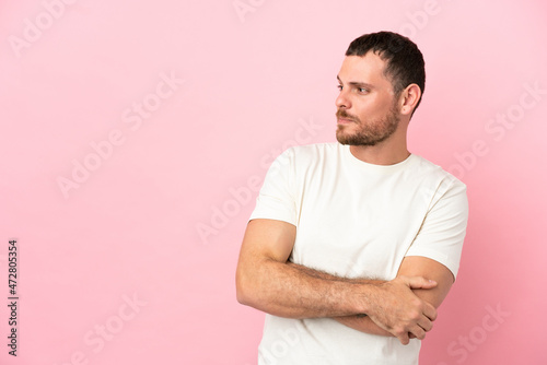 Young Brazilian man isolated on pink background looking to the side