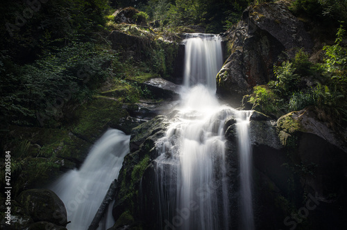 Idyllic waterfall falls into a dark gorge.