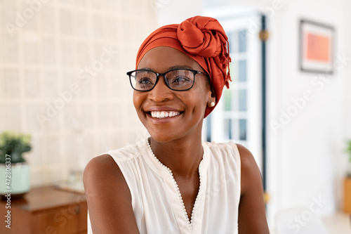 Fotografie, Obraz Happy smiling black woman with spectacles wearing african turban