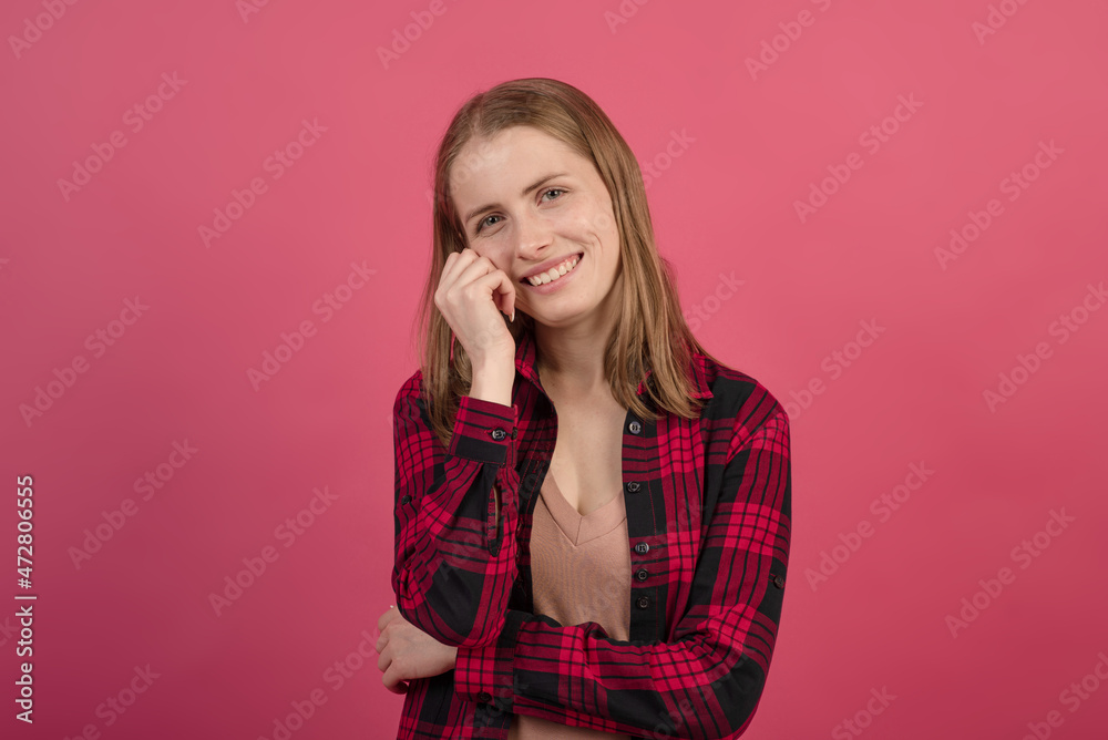 Portrait of a young and attractive Caucasian blonde girl in a shirt laughing on a pink studio background. Portrait of a young and attractive Caucasian blonde girl in a shirt laughing on a pink studio background.