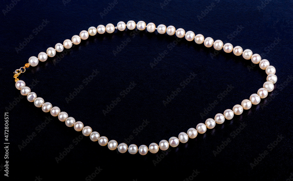 Pearl necklace on a dark blue leatherette background. Pearl necklace on a dark blue leatherette background.