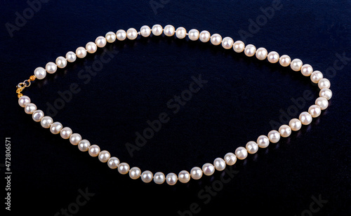 Pearl necklace on a dark blue leatherette background.