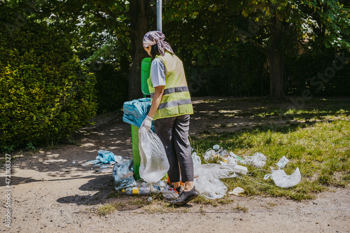 Young female environmentalist throwing plastic waste in garbage bin photo