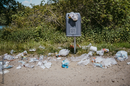 Garbage bin littered with plastic wastes around in park