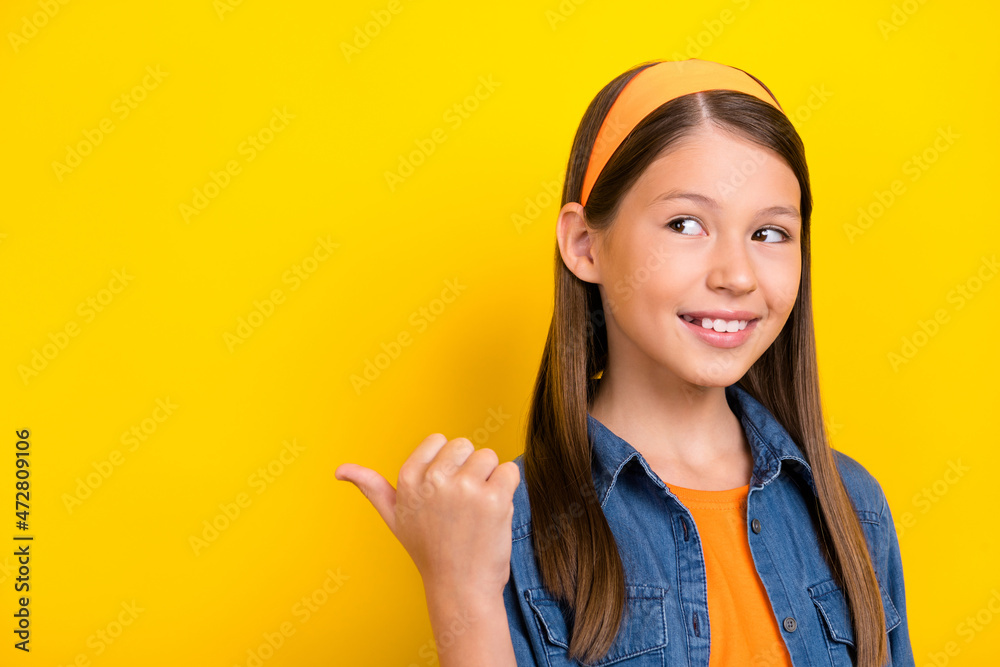 Photo of funky dreamy student girl wear denim shirt smiling looking pointing thumb up back empty space isolated yellow color background Photo of funky dreamy student girl wear denim shirt smiling looking pointing thumb up back empty space isolated yellow color background
