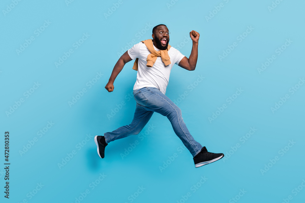 Fototapeta premium Photo of shopaholic guy jump rush forward crazy mood wear t-shirt jumper front-tie isolated blue color background