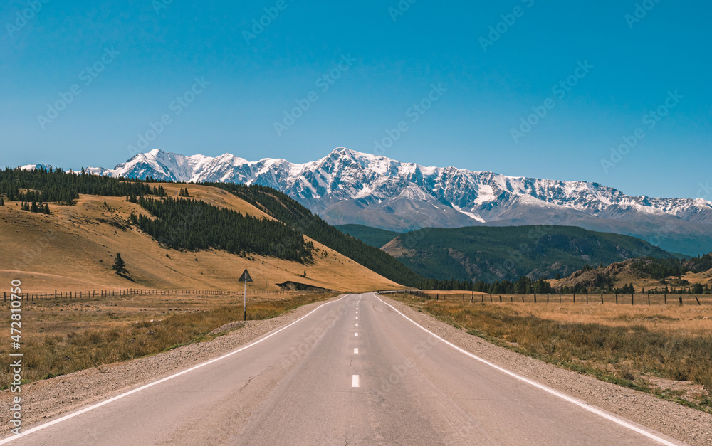 Fototapeta premium Empty asphalt road in front of huge majestic mountains with snow covered peaks. Beautiful landscape of Altay region, Russia.