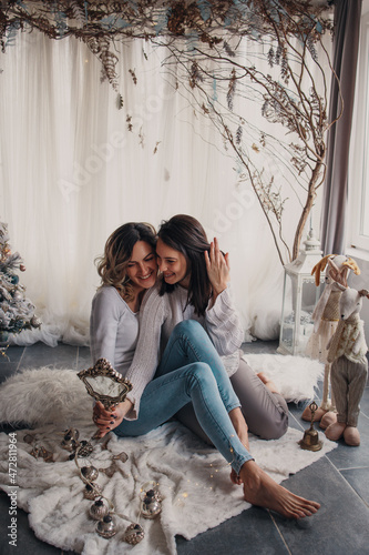 Two young women sitting on the flor with christmass decoration