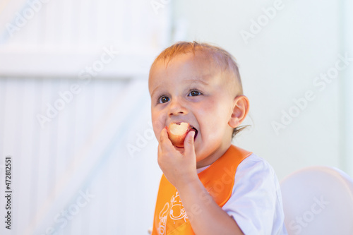 Little toddler boy eating sweet pearch outdoor in summer on white background. Tasty healthy vitamin snack for children. photo