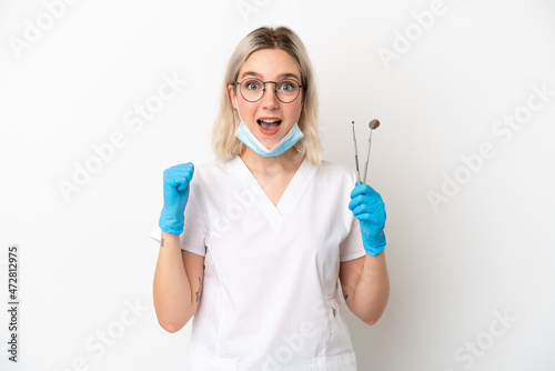 Dentist caucasian woman holding tools isolated on white background celebrating a victory in winner position