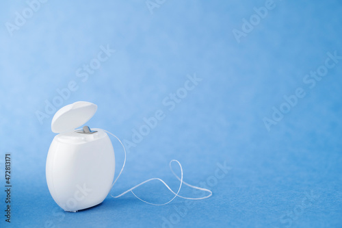 Container with dental floss. Floss on blue background. White dental floss case isolated. Open dental floss container. High quality photo photo