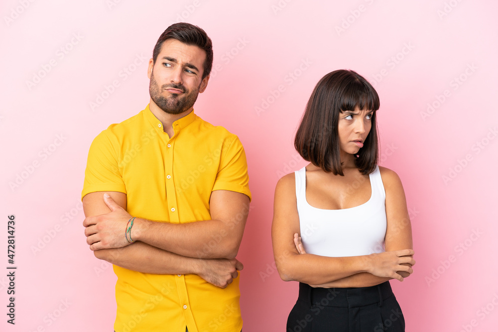Young couple isolated on pink background with confuse face expression while bites lip Young couple isolated on pink background with confuse face expression while bites lip