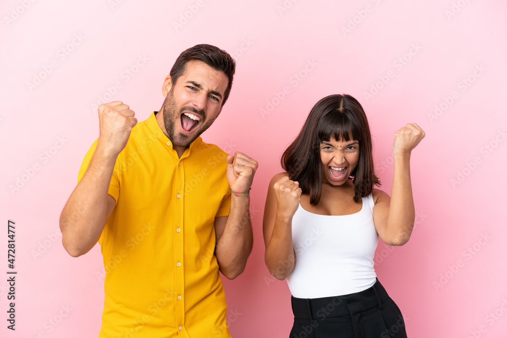 Young couple isolated on pink background celebrating a victory Young couple isolated on pink background celebrating a victory