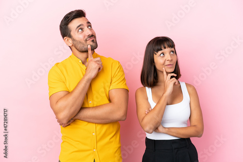 Young couple isolated on pink background thinking an idea while looking up