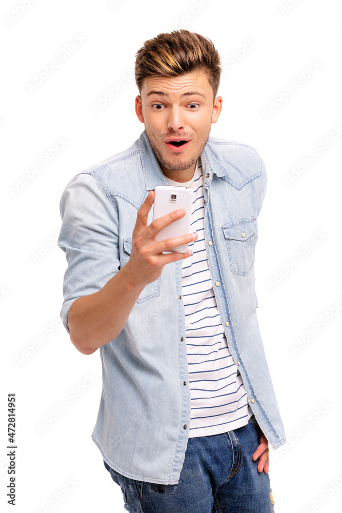 Shocked news! Studio portrait of amazed young man using smartphone. Isolated on white.