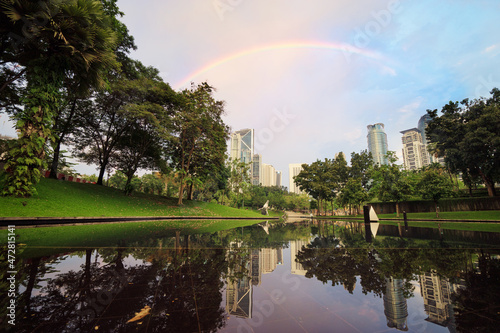 Beautiful cityscape with rainbow in the sky. The pool in the city park.