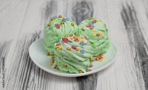 Green mojito flavored marshmallow (Zefir) garnished with multicolored sugar confectionery sprinkles. Festively decorated sweets to serve on the table for a holiday. New Year, Christmas, birthday.