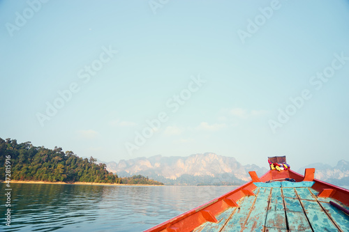 Wooden boat with water, sky and mountains in Ratchaprapha Dam or Khao sok national park, Thailand