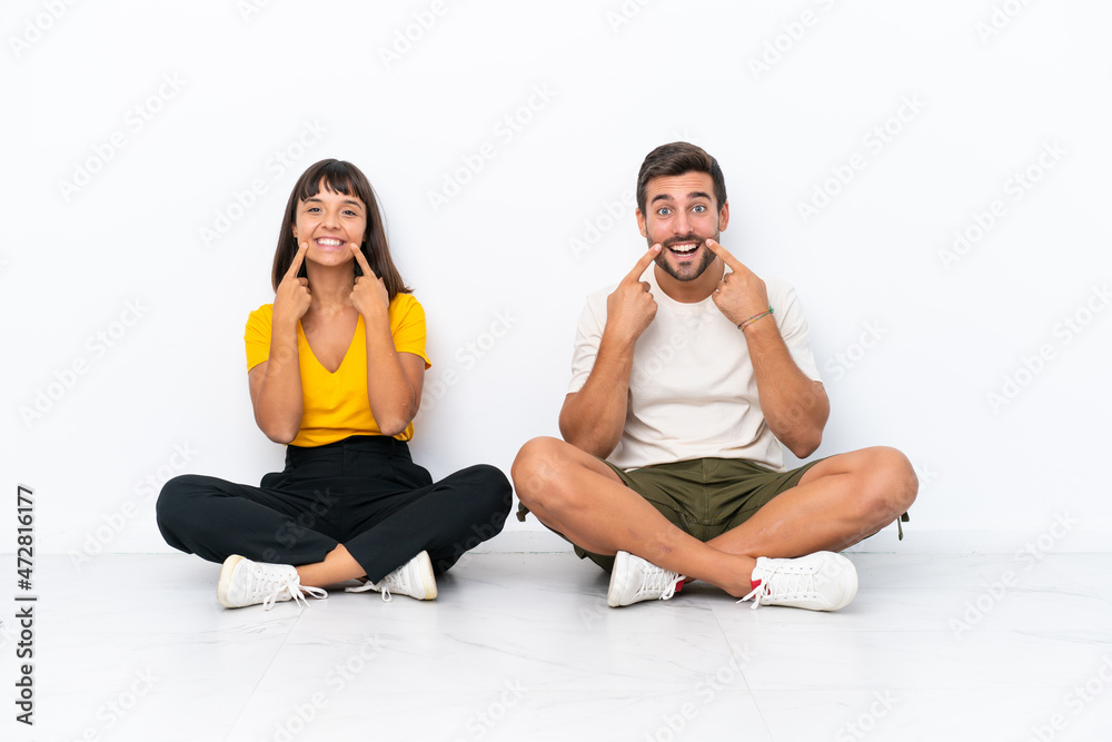 Young couple sitting on the floor isolated on white background smiling with a happy and pleasant expression Young couple sitting on the floor isolated on white background smiling with a happy and pleasant expression