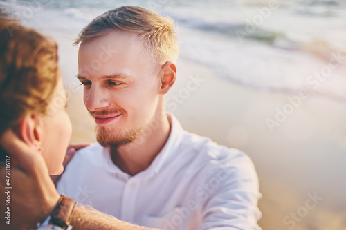 Romantic vacation. Love and tenderness. Young loving couple kissing and embracing on the sea sand beach.