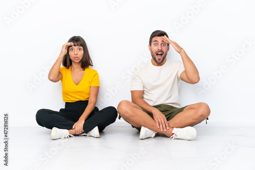 Young couple sitting on the floor isolated on white background has just realized something and has intending the solution